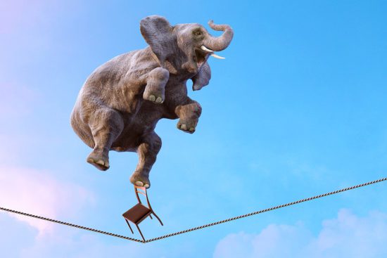 Elephant balancing on the tightrope high in the sky above clouds